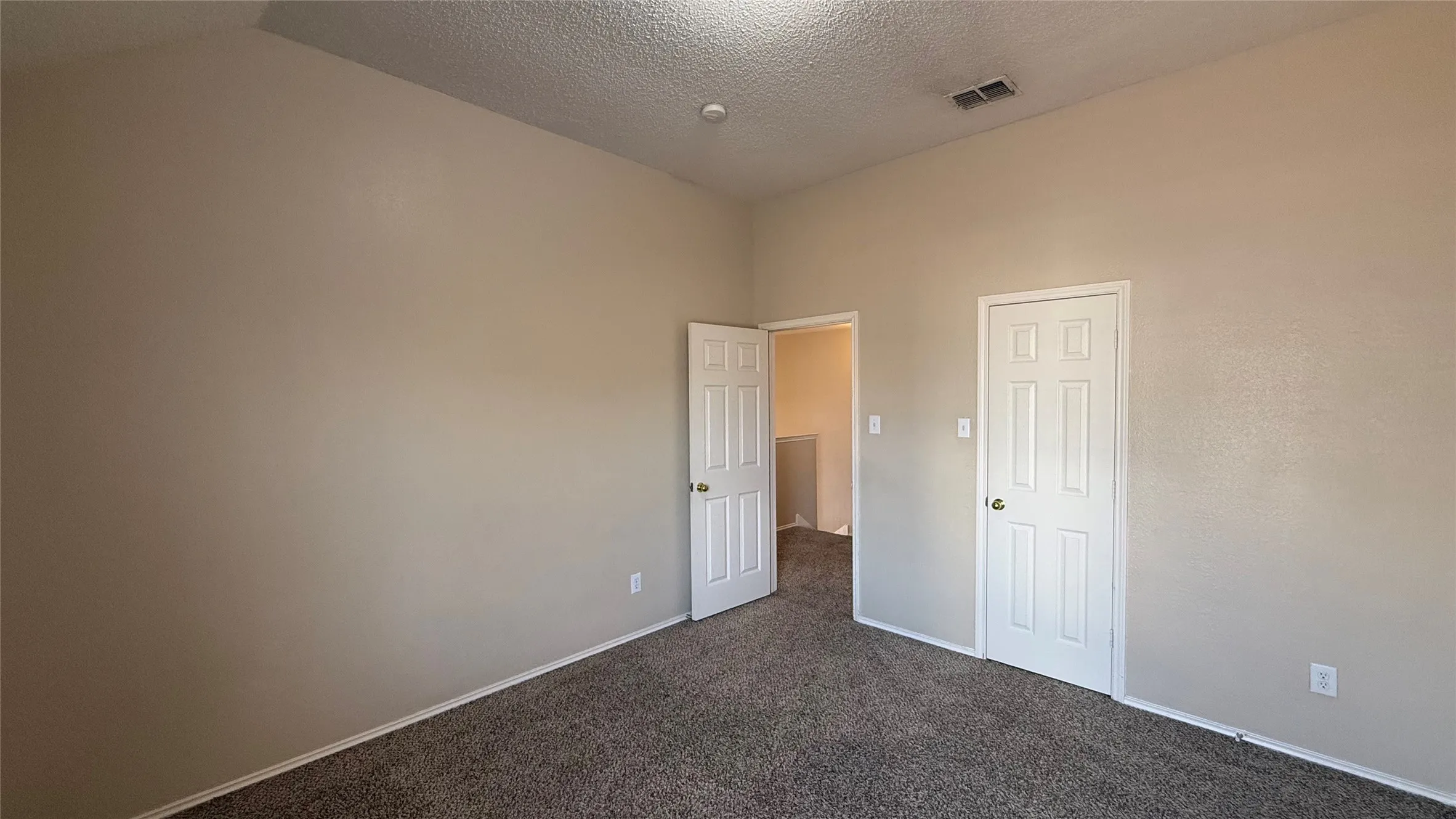 Plush carpeting, neutral wall finishes, white six-panel doors, and a vaulted ceiling