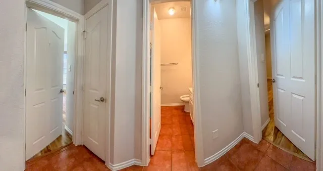 Terracotta-style tile flooring with white baseboards, featuring white paneled doors with brushed nickel hardware