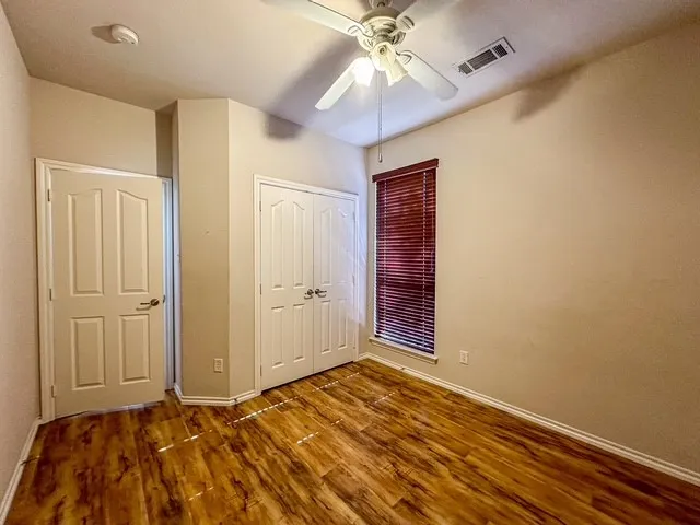 Wood-finish flooring, ceiling fan, and window with blinds