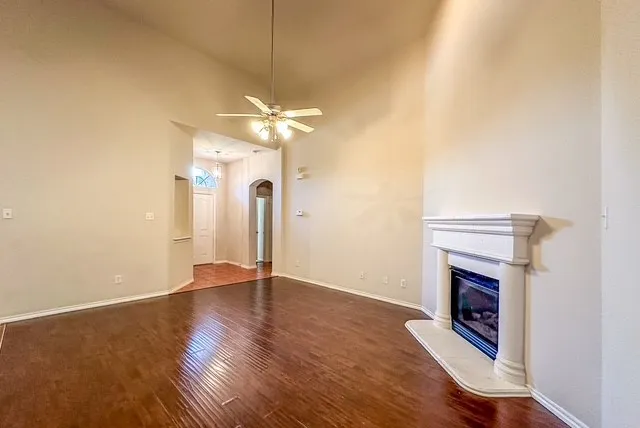 Vaulted ceilings, wood-finish flooring, built-in fireplace, ceiling fan, and arched entryway
