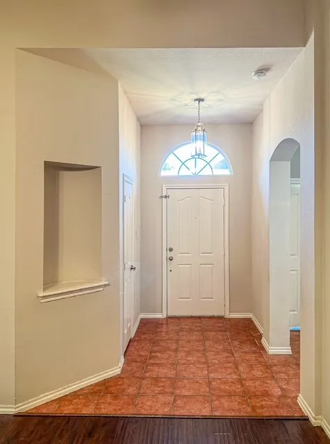 Front entry featuring a paneled door with an arched transom window, a hanging lantern light fixture, and tile flooring