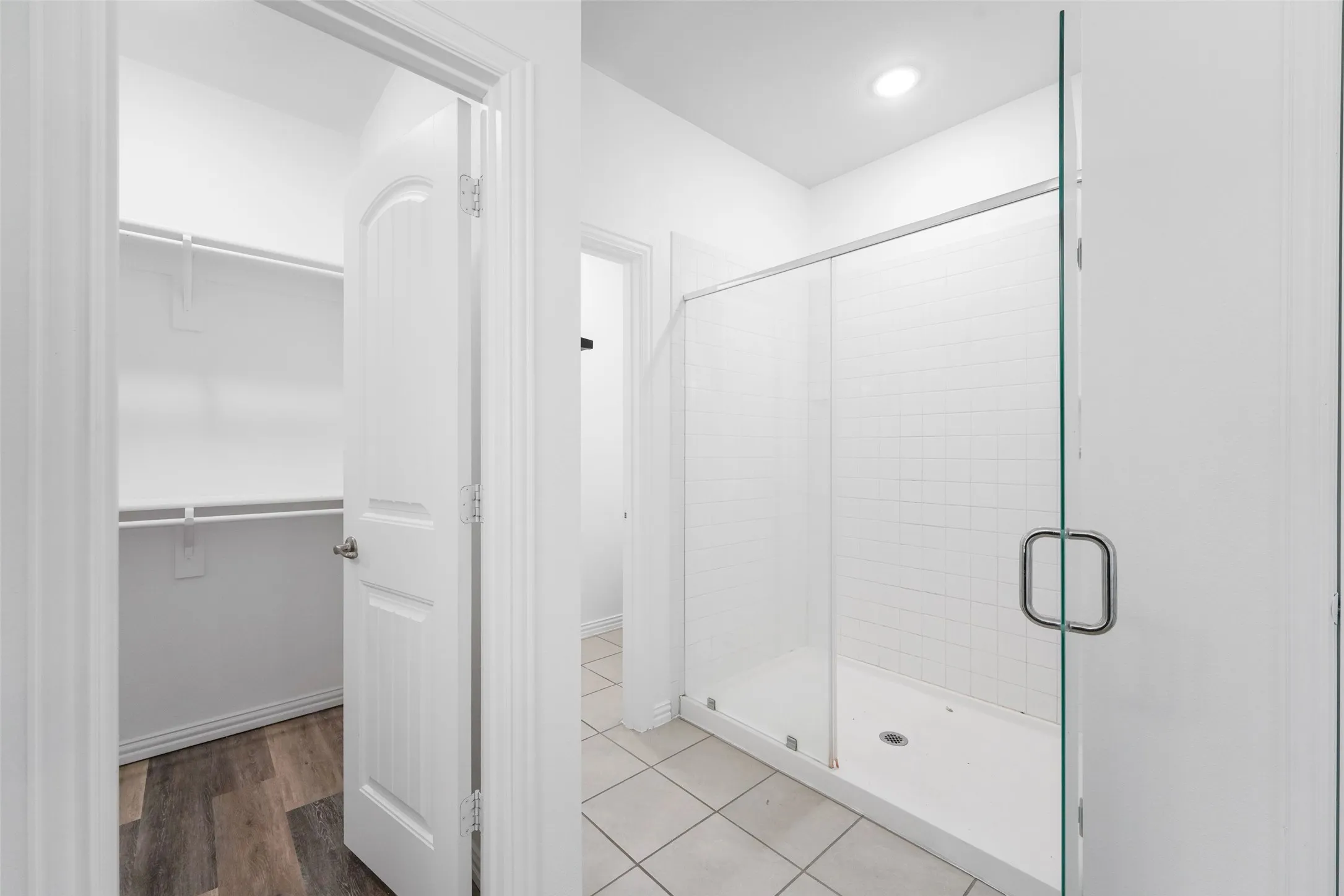 Primary Bathroom Featuring Frameless Glass Shower Enclosure with Chrome Hardware, Ceramic Tile Flooring, Recessed Ceiling Lighting, and Clean White Subway Tile Shower Surround with Built-In Shelf