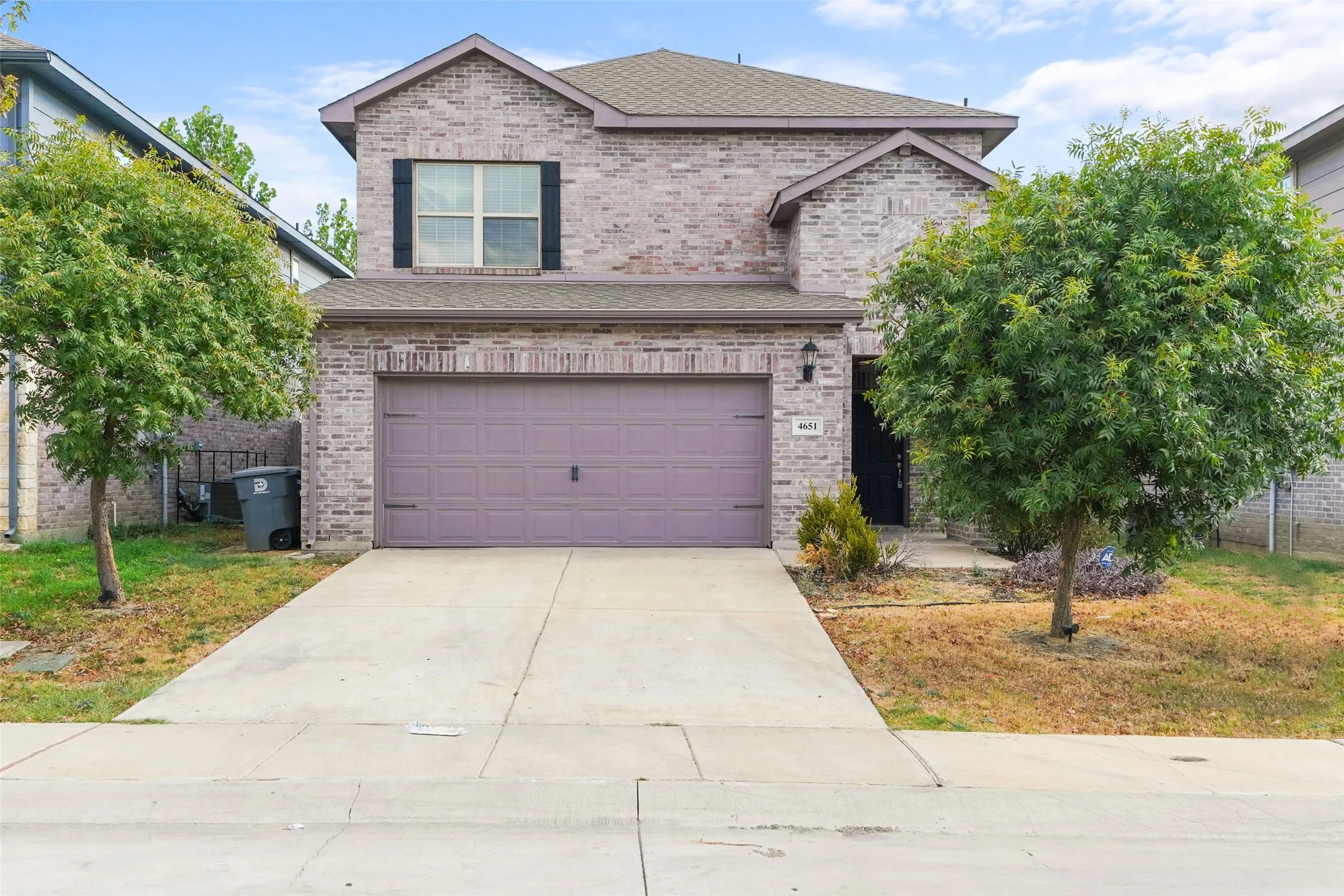 Brick exterior featuring a two-car garage, concrete driveway, and front entryway