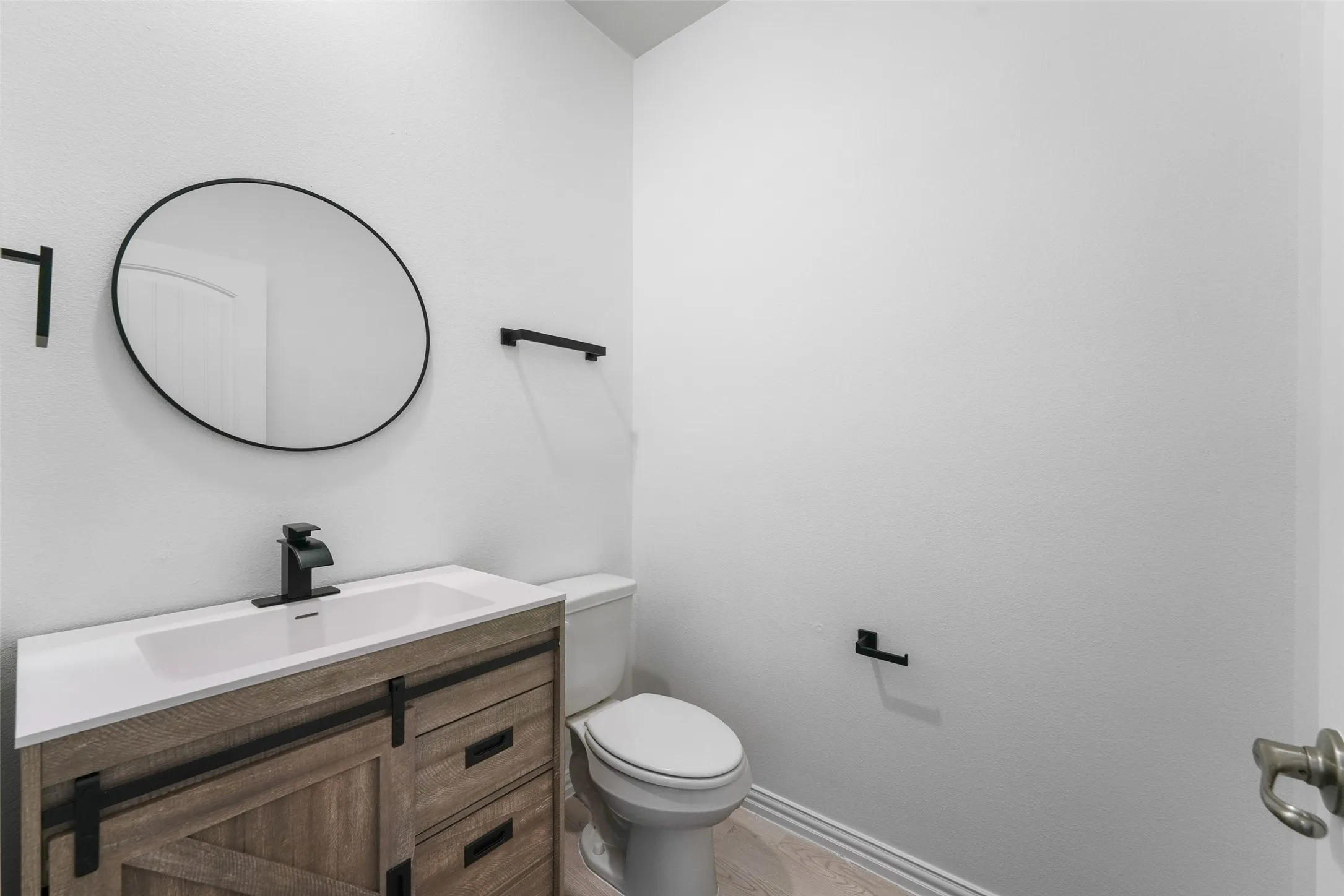Modern vanity with a white integrated sink, matte black faucet, and round mirror