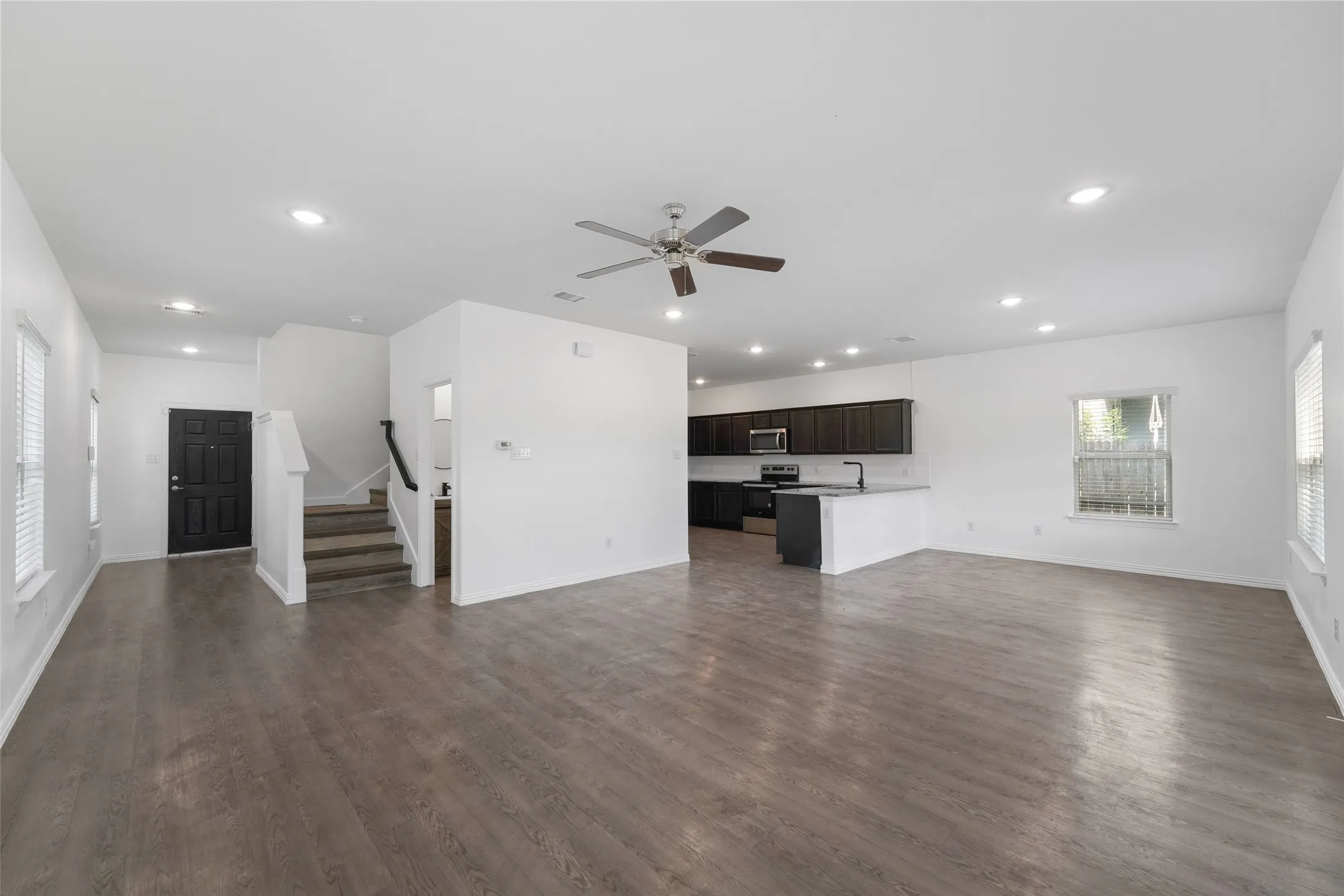 Open-concept living space featuring wood-finish flooring, recessed lighting, and a ceiling fan