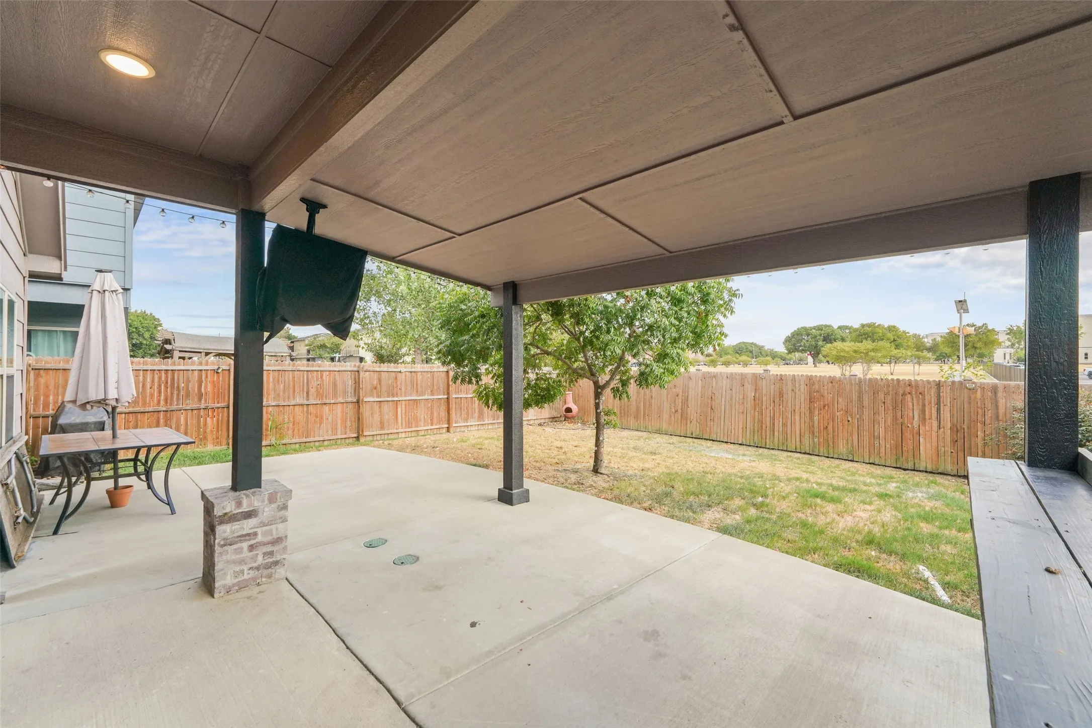 Covered patio with recessed lighting, concrete flooring, and brick-wrapped support columns