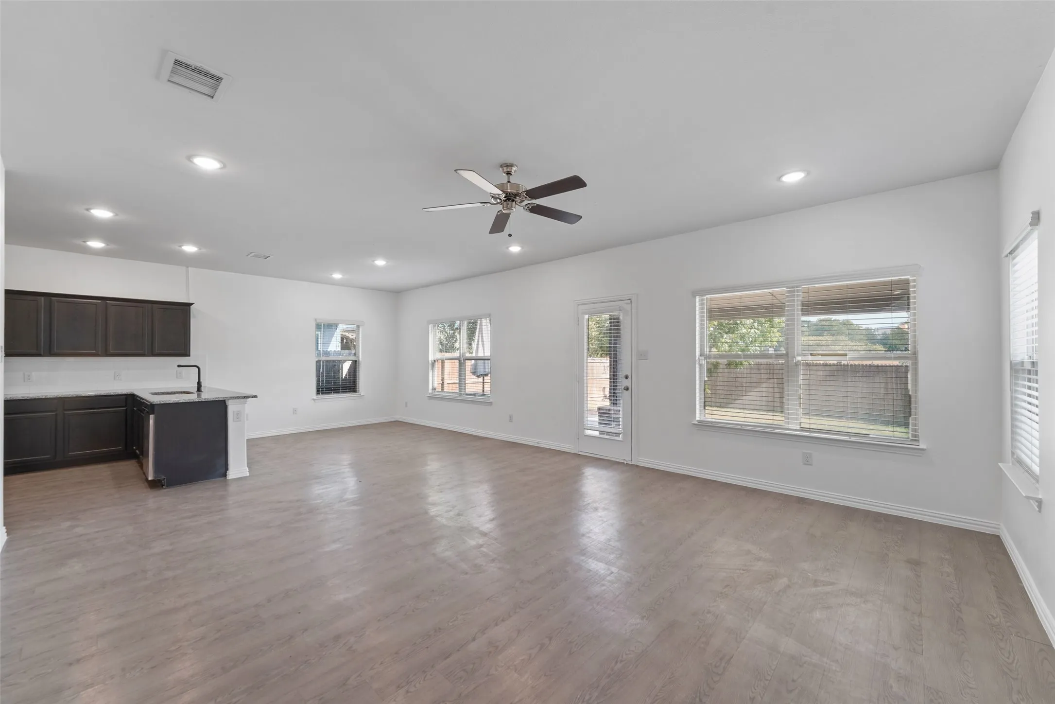 Open-concept living area with wood-finish flooring, recessed lighting, and a ceiling fan