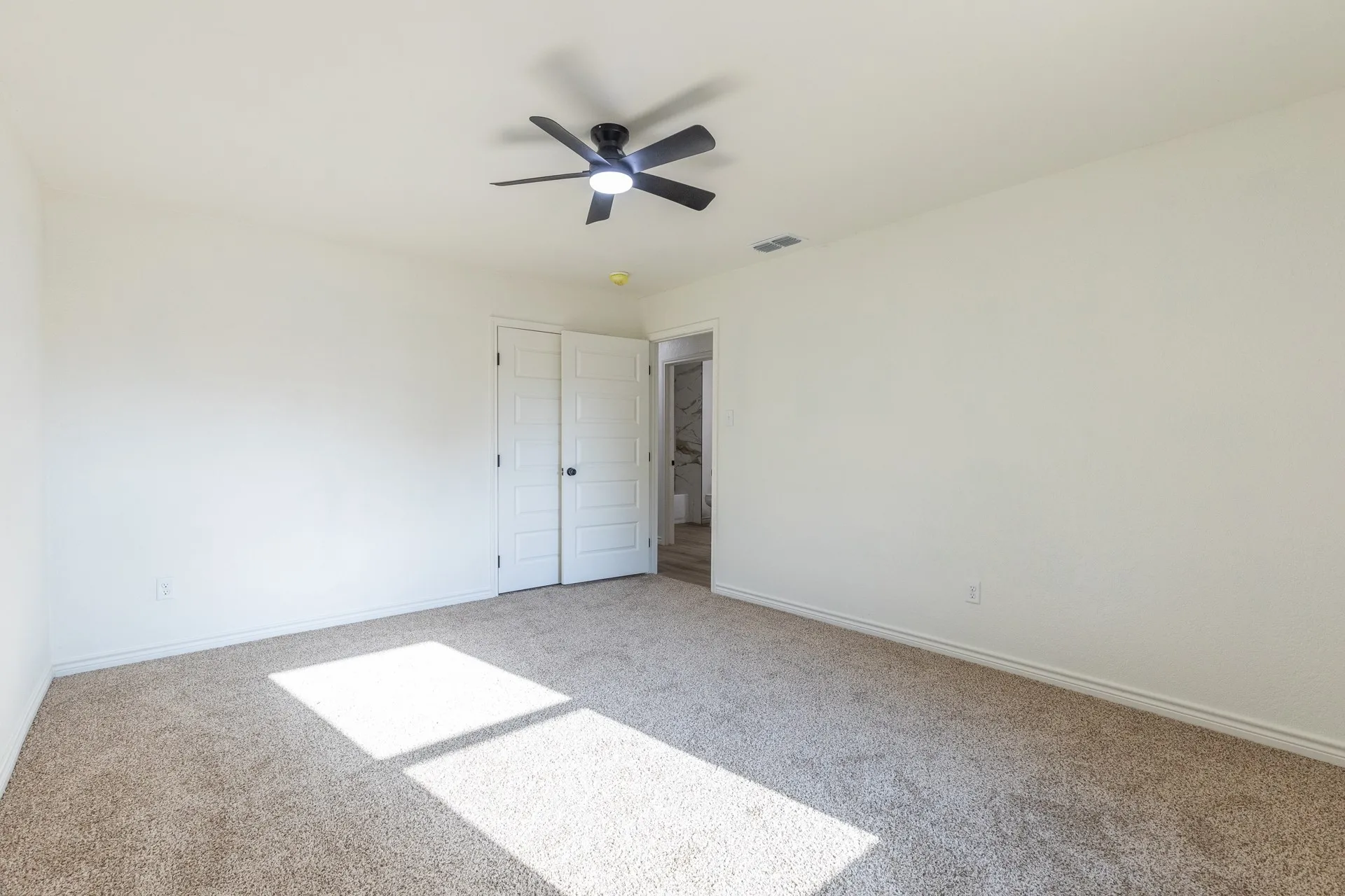 Neutral wall paint, ceiling fan with integrated lighting, textured carpet flooring, double panel closet doors