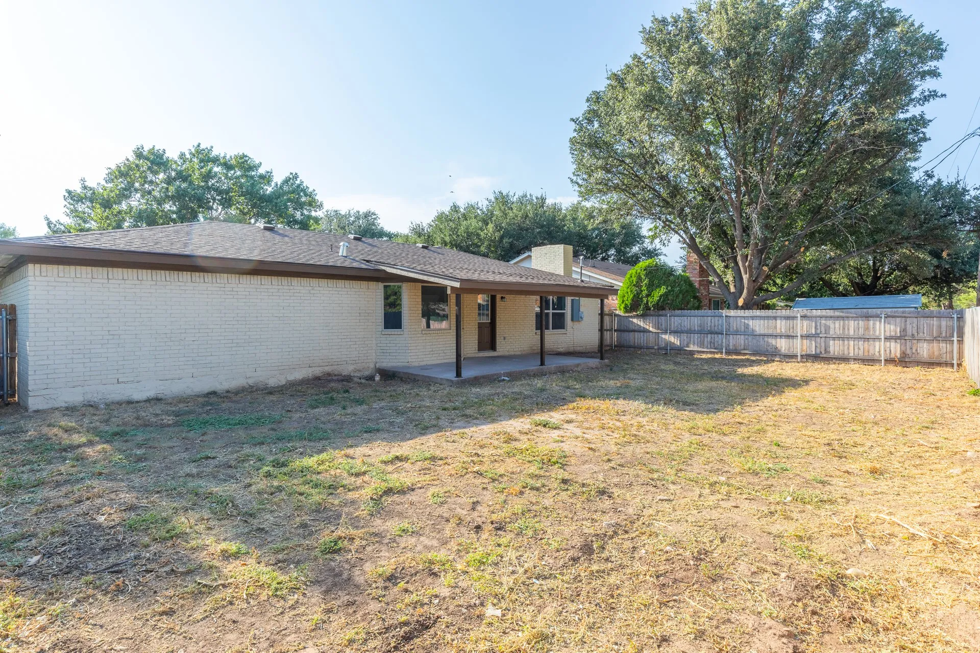 Expansive backyard featuring a privacy fence and mature trees