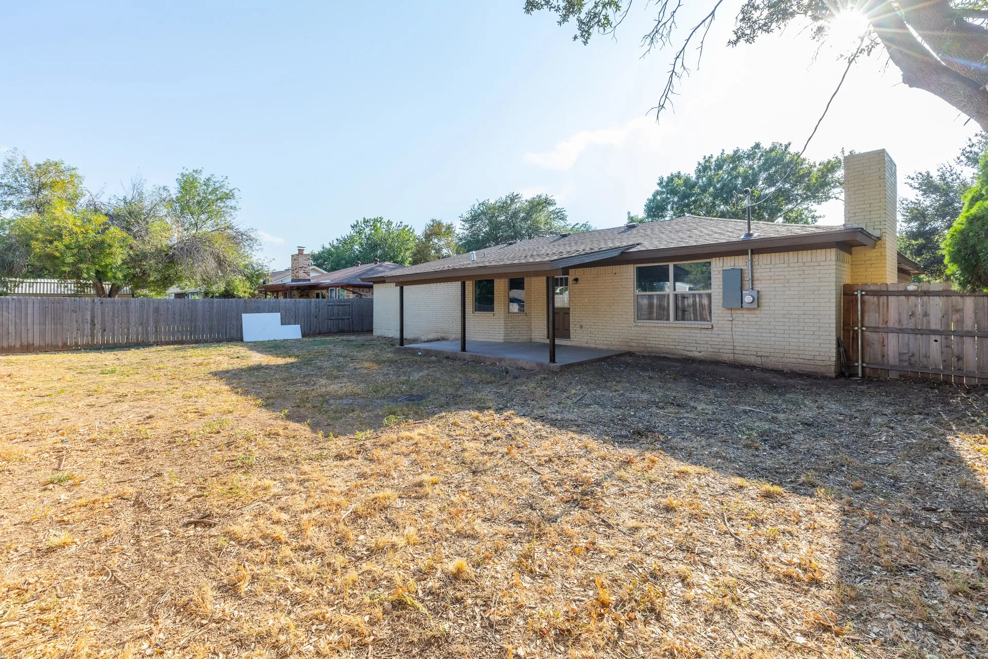 Expansive backyard with a full privacy fence and a covered patio