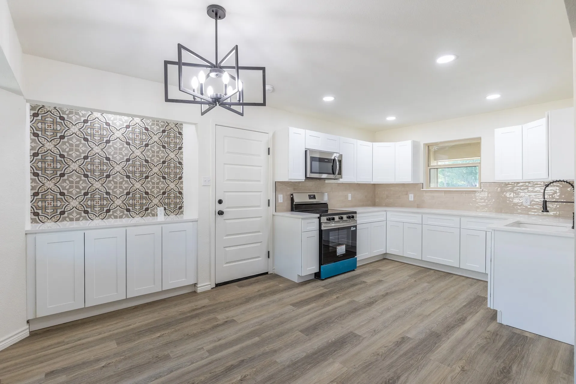 Modern kitchen featuring wood-finish flooring, white cabinetry, recessed lighting, and a stainless steel microwave