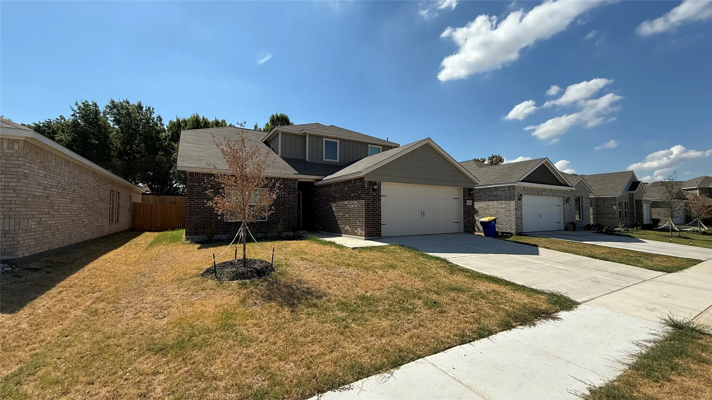 Brick and siding exterior with an attached two-car garage, concrete driveway, and a fenced backyard