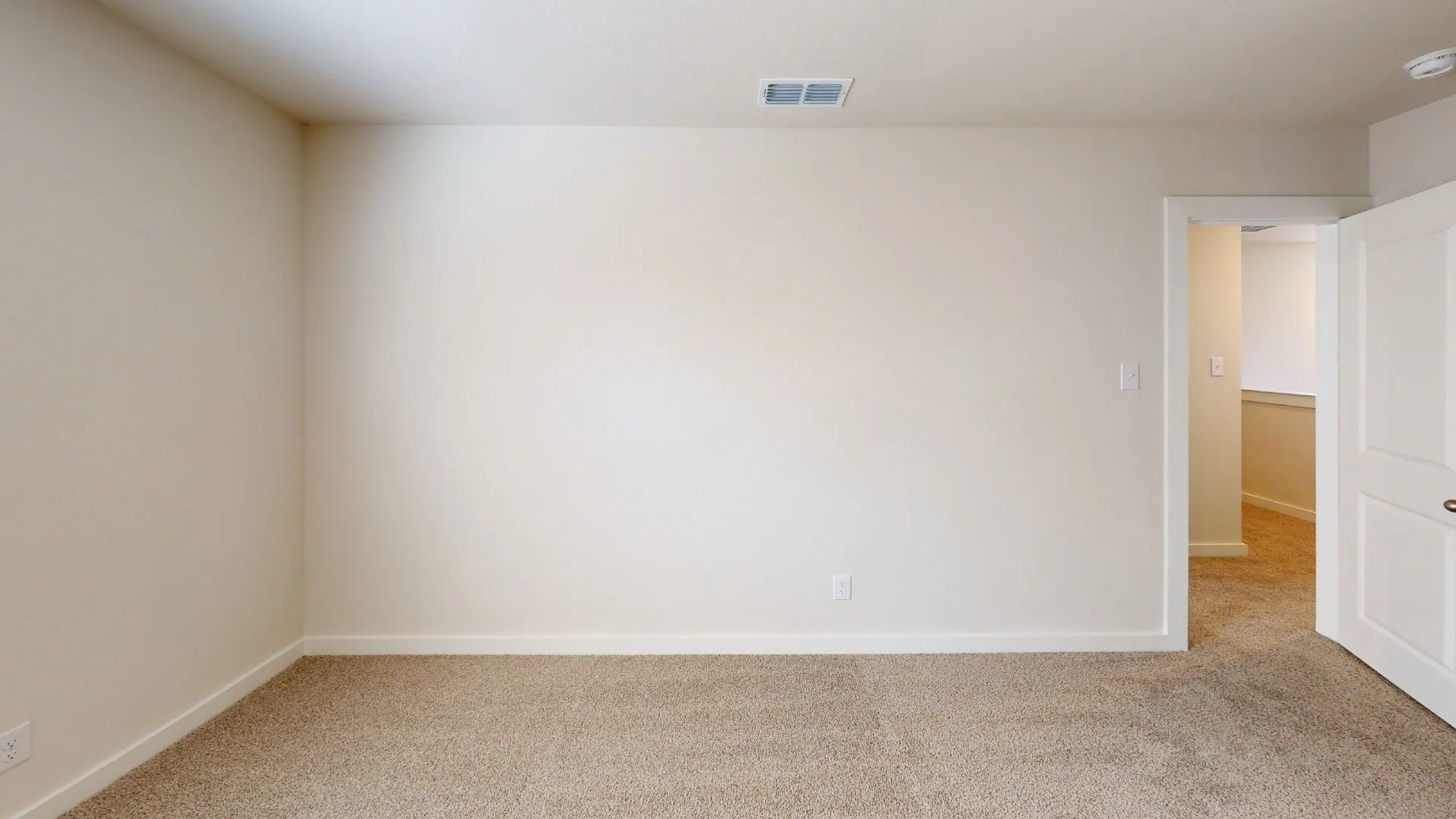 Neutral tone wall paint, light-toned carpeting, white trim, and a paneled interior door