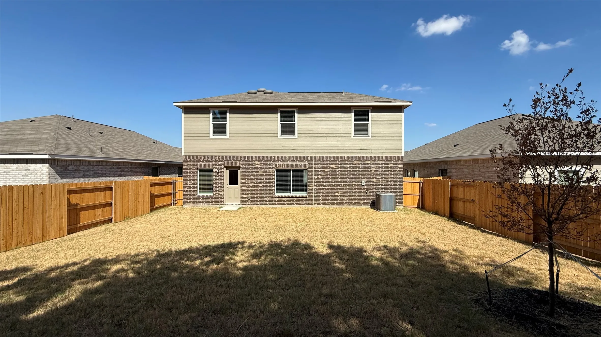 Two-story exterior with brick and siding facade, private fenced backyard, and a ground-level exterior door