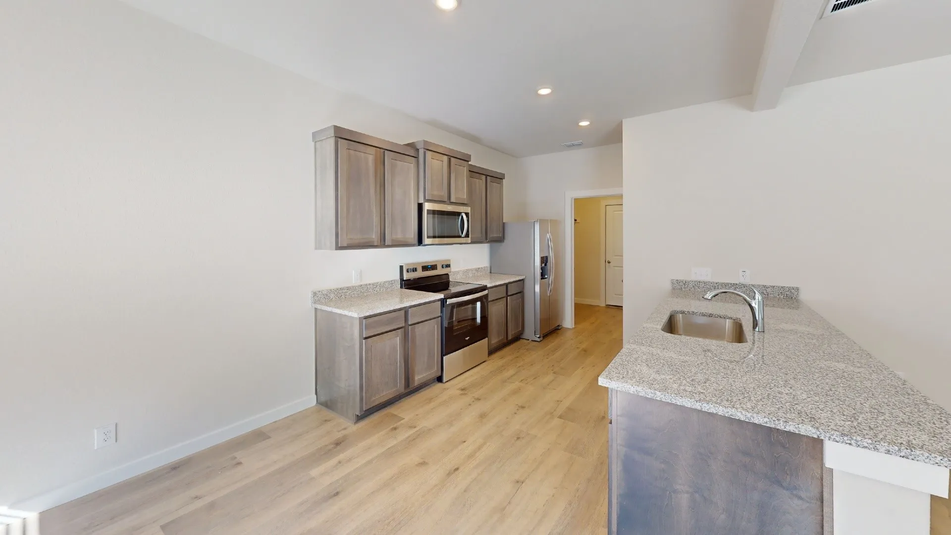 Kitchen featuring wood-finish flooring, recessed lighting, stainless steel appliances, grey cabinetry, and speckled countertops