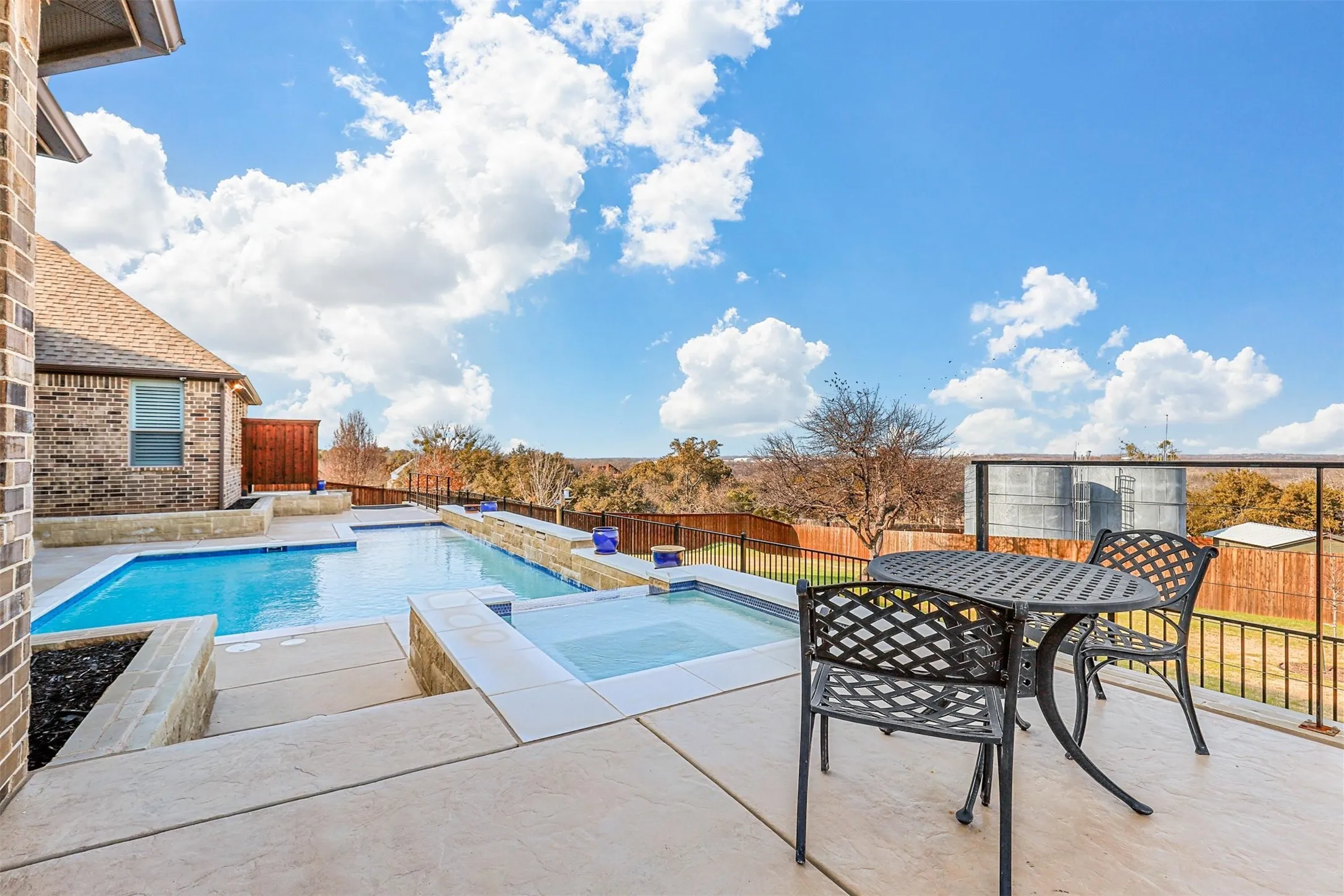 Expansive concrete patio with a built-in swimming pool and integrated spa