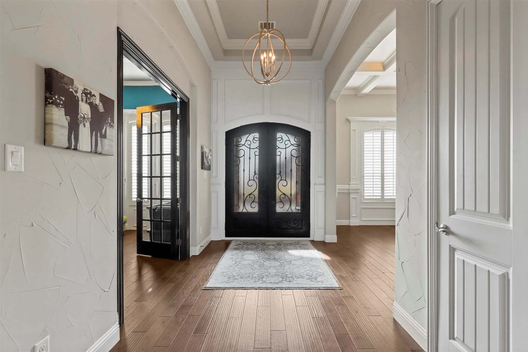 Grand entryway featuring wood-finish flooring, an ornate double entry door, and a coffered ceiling with a chandelier