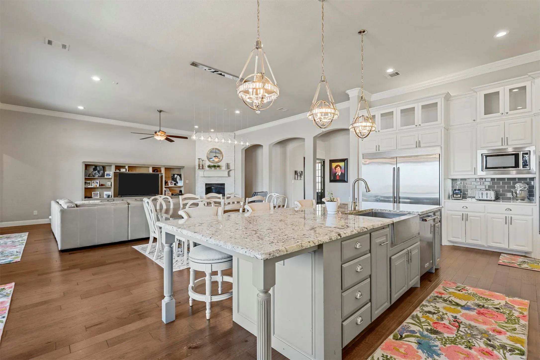 Open concept living space featuring wood-finish flooring, a kitchen island with stone countertop, stainless steel appliances, a fireplace, and recessed lighting