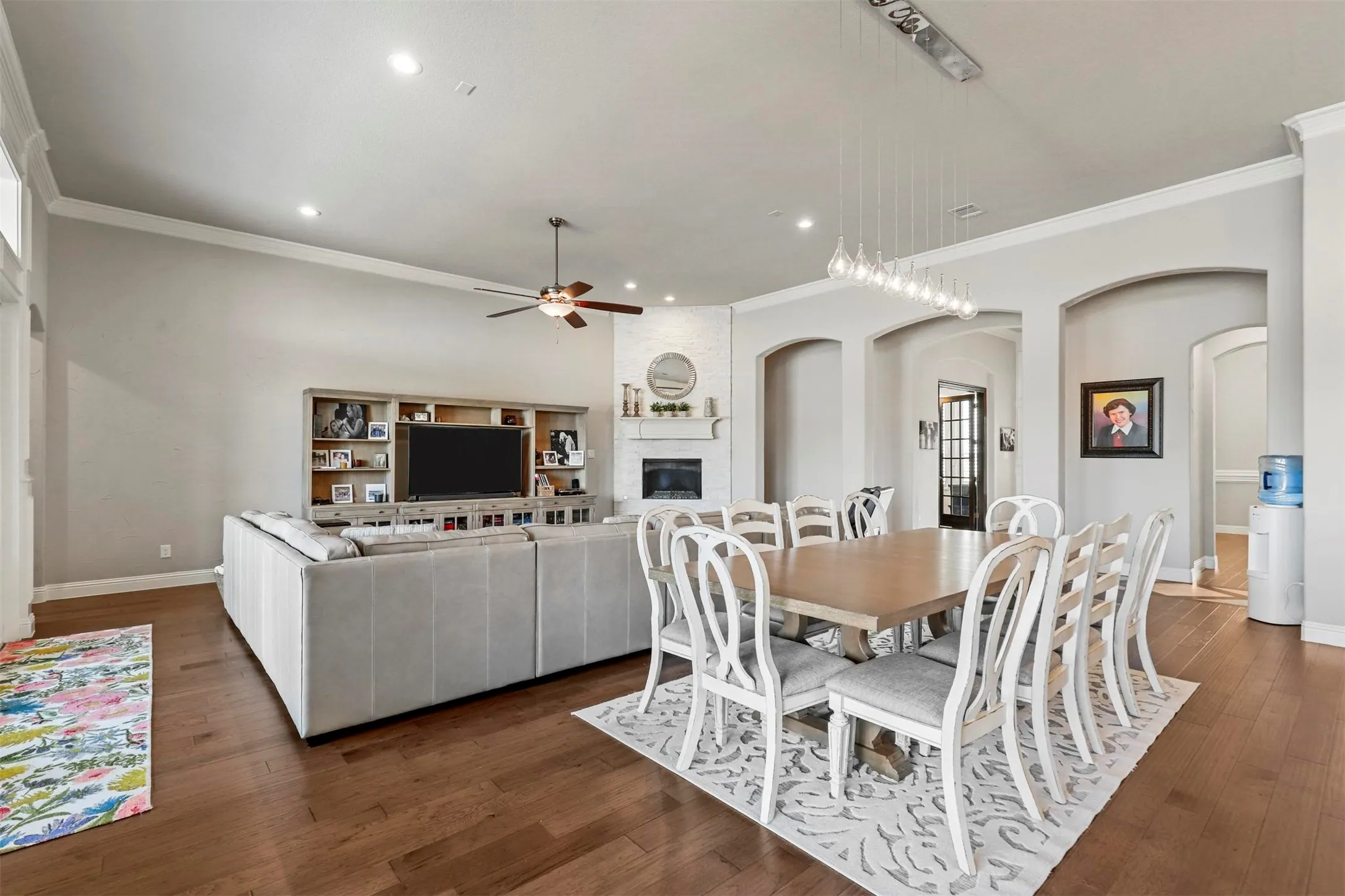 Hardwood flooring throughout, recessed ceiling lighting, built-in shelving, fireplace with mantel, and arched doorways