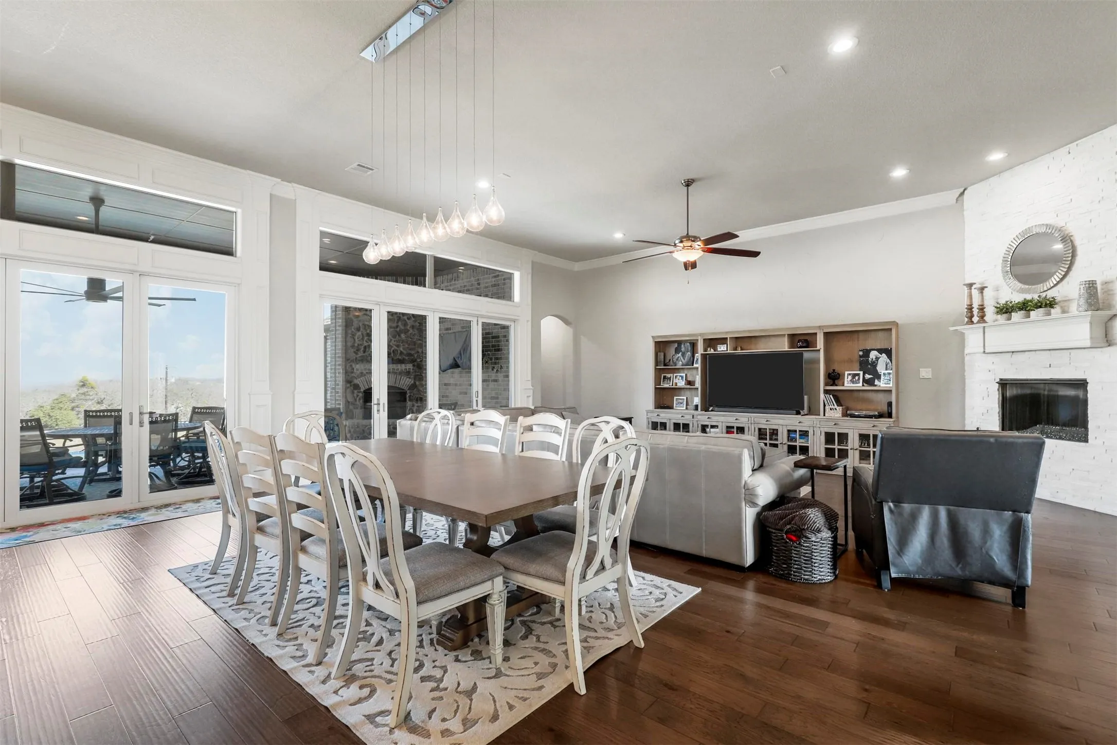 Open-concept living space with dark wood-finish flooring, a white brick fireplace, and a built-in entertainment center