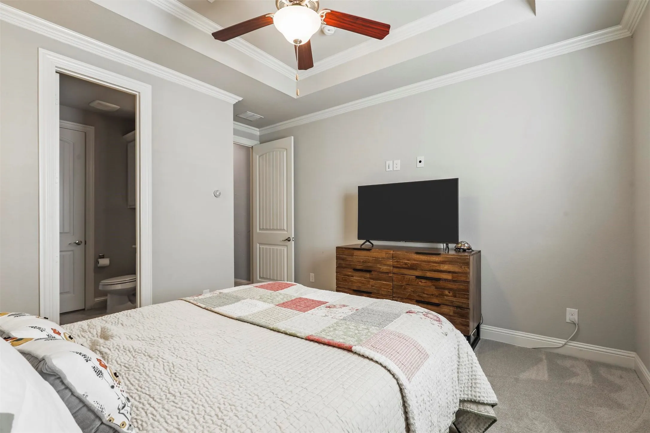 Tray ceiling with a ceiling fan, crown molding, and light gray wall paint