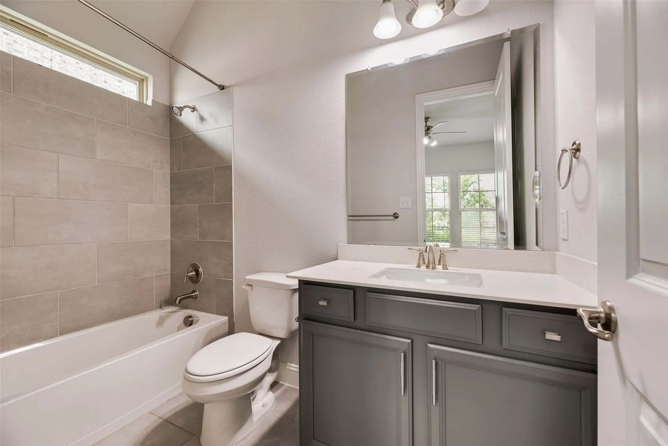 Full bathroom with a white tub and shower featuring large format gray tile surround