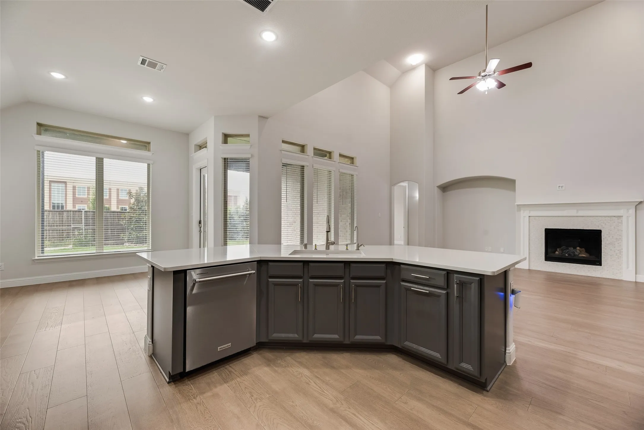Kitchen island with a built-in stainless steel dishwasher, a white countertop, and under-counter cabinetry