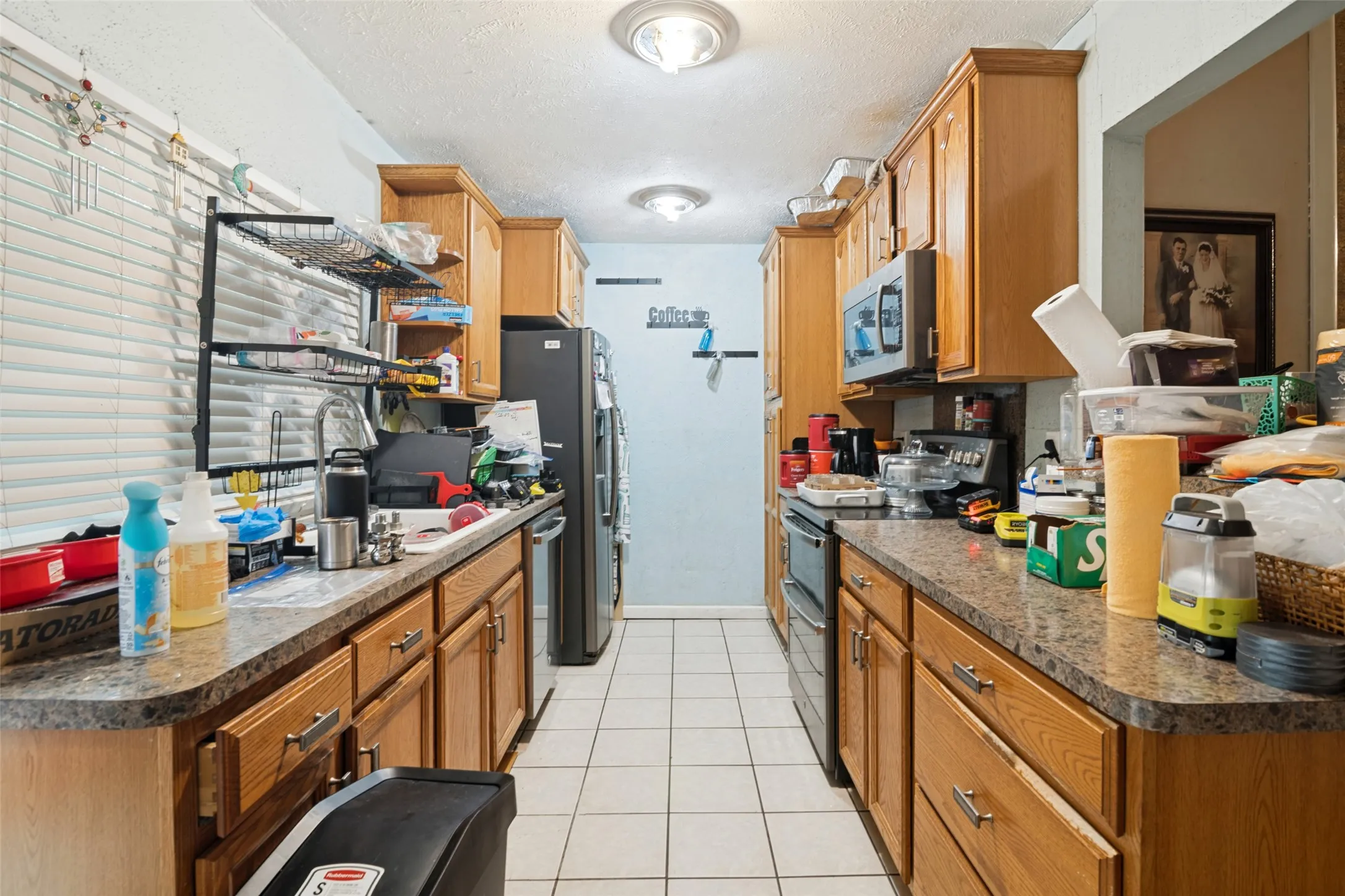 Galley kitchen with wood-finish cabinetry, speckled countertops, and tile flooring