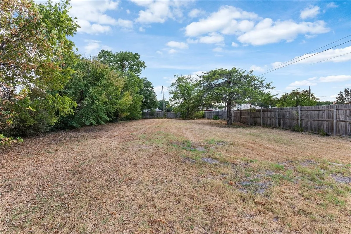 Expansive lot featuring a wooden privacy fence and mature trees