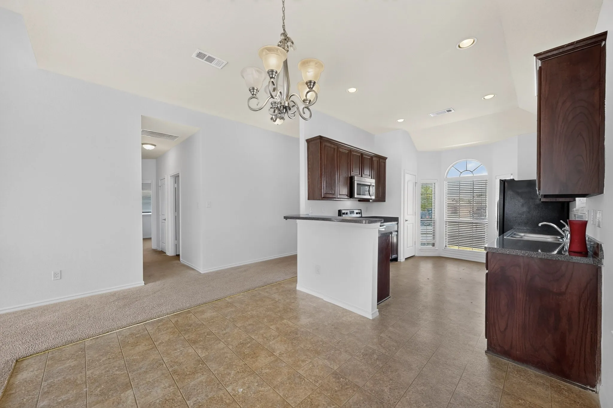 Kitchen featuring dark wood-finish cabinetry, black countertops, and a built-in microwave