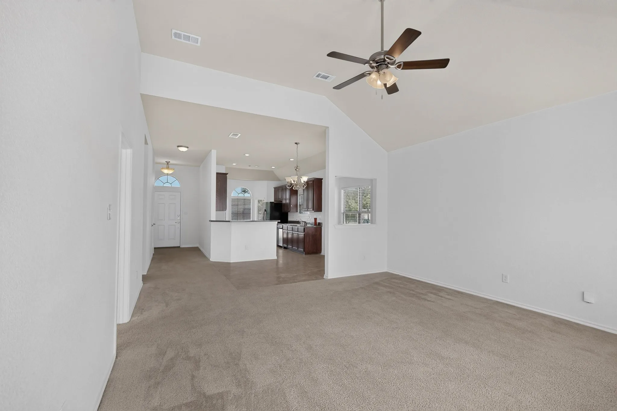 Vaulted ceiling, ceiling fan, carpet flooring, recessed lighting, and kitchen pass-through