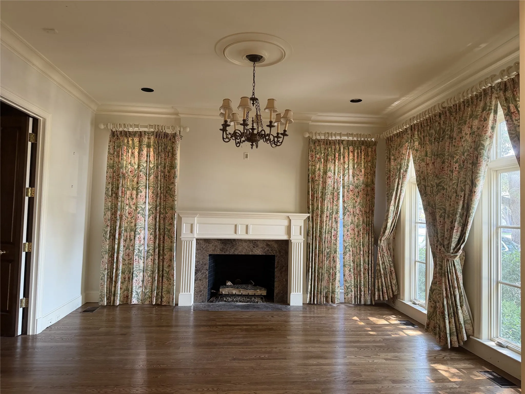 Formal living with lovely crown molding, fireplace with decorative mantle surround, hard wood floors, floor to ceiling windows.