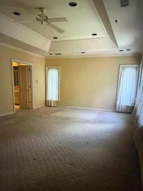 Primary bedroom with tray ceilings and wall of windows.