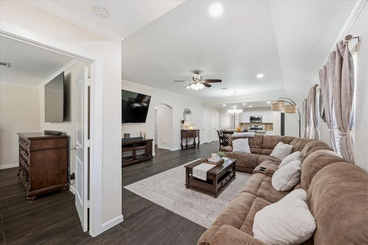 Wood-finish flooring, recessed lighting, arched doorway, ceiling fan, and crown molding