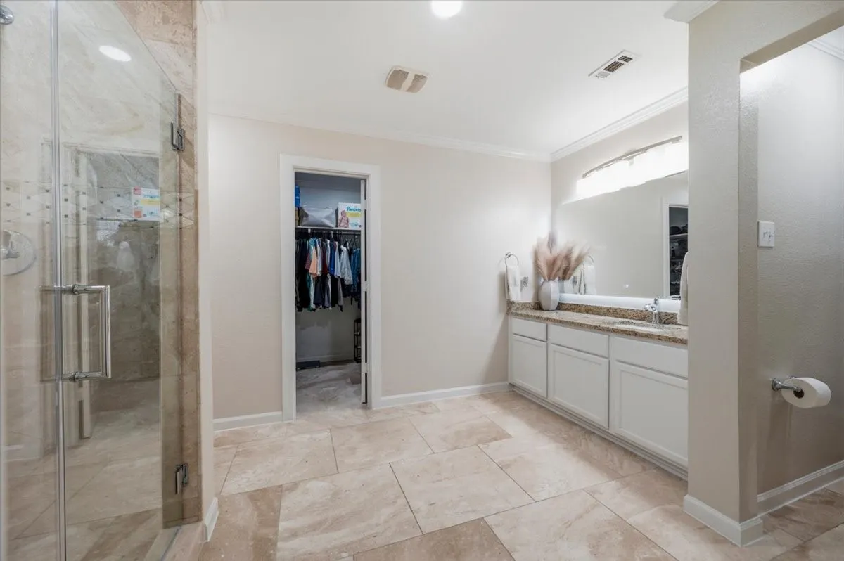 Tiled flooring, glass-enclosed shower, built-in vanity with countertop, large mirror, and recessed lighting