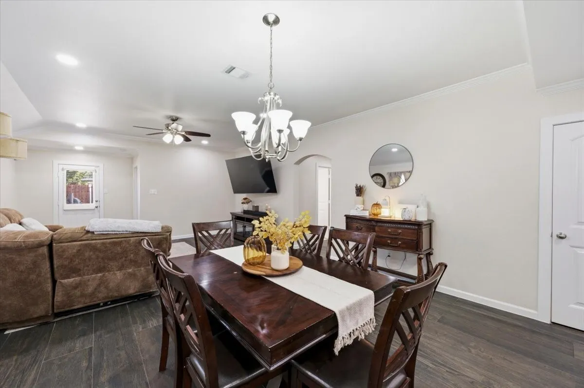 Open-concept dining and living areas with wood-finish flooring, recessed lighting, and a chandelier
