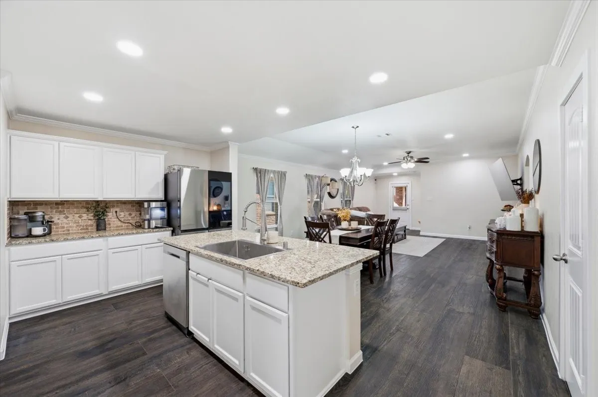 White cabinetry with integrated stainless steel appliances, granite countertops, and a tile backsplash