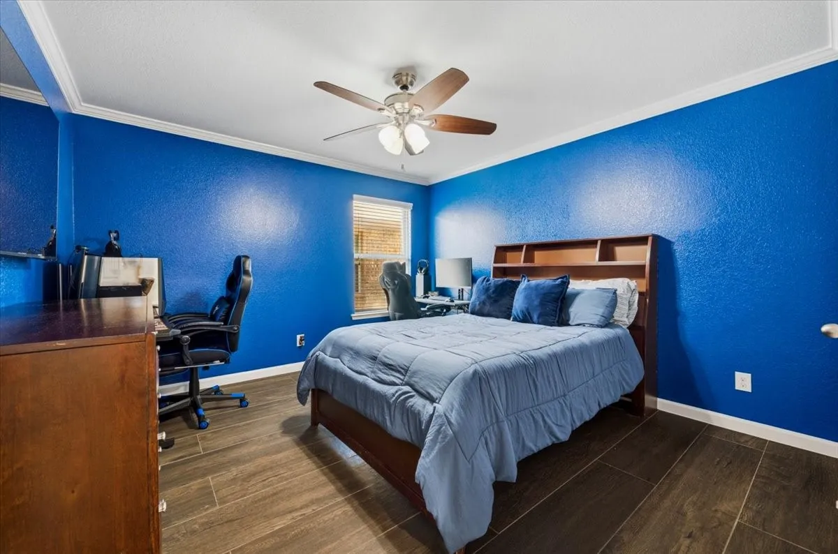 Wood-finish flooring, crown molding, built-in shelving, ceiling fan, and recessed window
