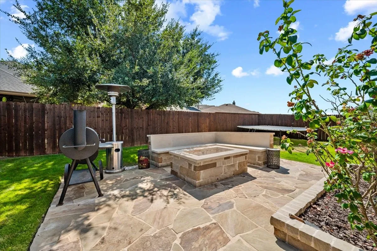 Outdoor patio featuring flagstone paving, a built-in fire pit, and a built-in stone bench