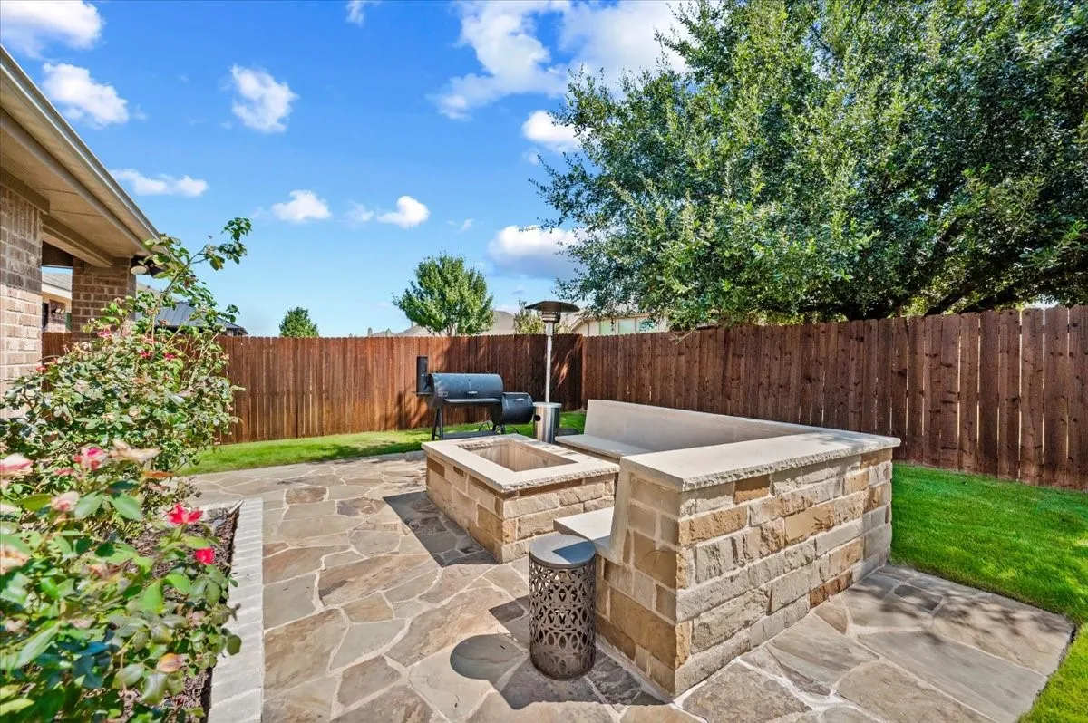Expansive flagstone patio with a built-in stone fire pit and integrated stone bench seating