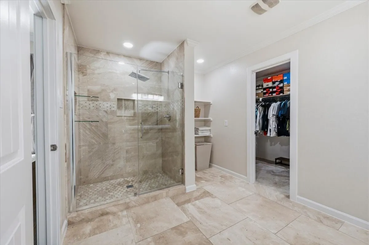 Walk-in shower with glass enclosure, tile surround, and rainfall showerhead