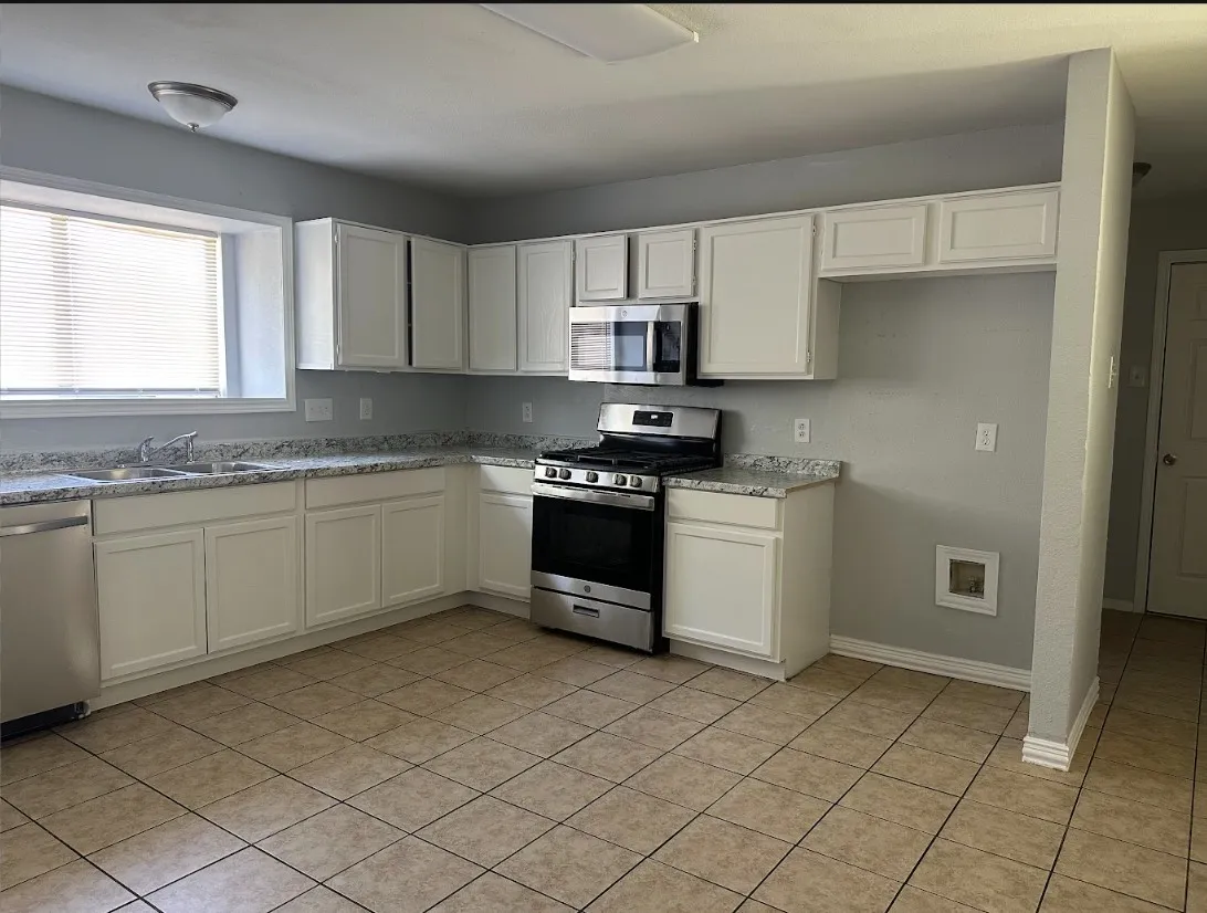 Kitchen featuring white cabinetry, light-toned tile flooring, and stainless steel appliances