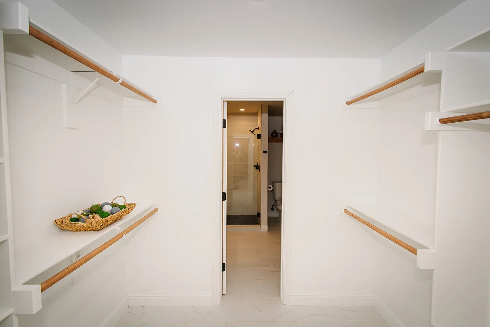 Walk-in closet with white shelving and wood hanging rods