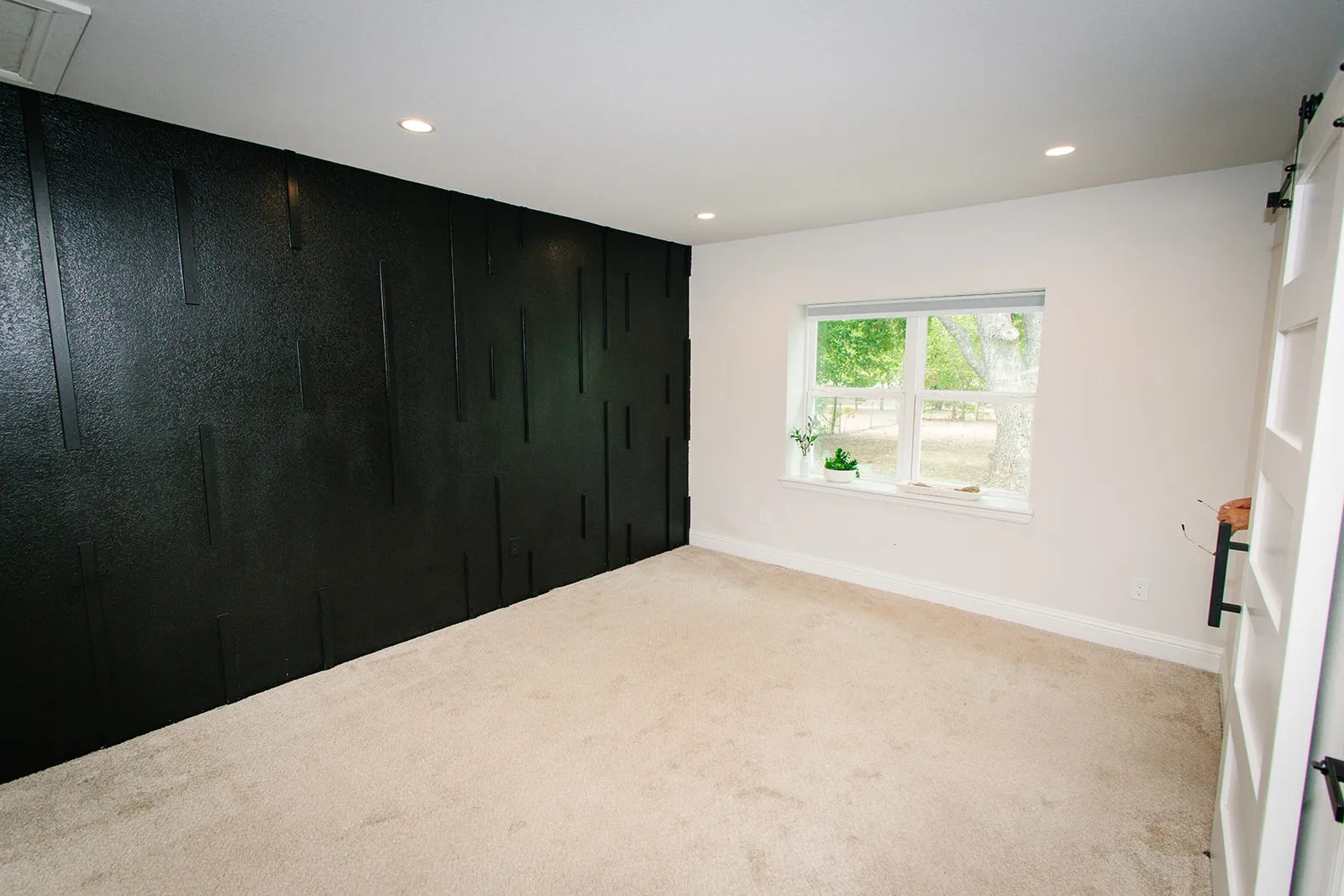 Master bedroom Textured accent wall, recessed ceiling lighting, light-toned carpeting, white window trim, and white walls