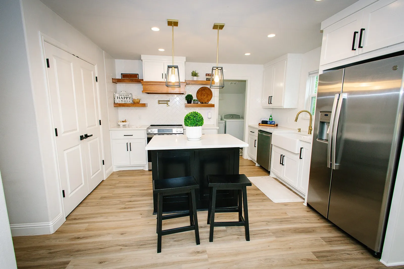 Kitchen featuring wood-finish flooring, white cabinetry, a central island with countertop, stainless steel appliances, and open shelving