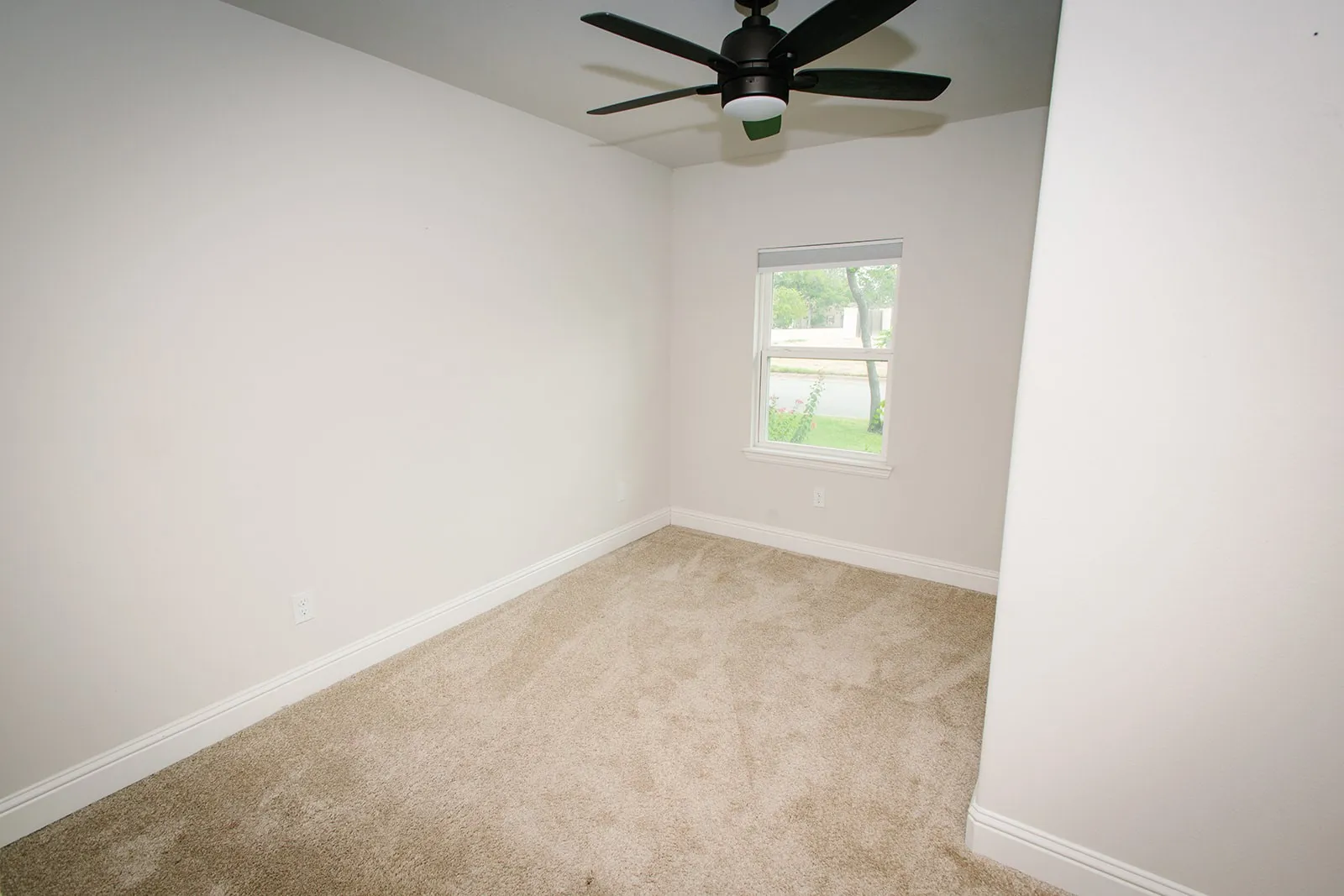BedroomWall-to-wall carpeting, single window with exterior scenery, ceiling fan with integrated lighting, and white baseboards