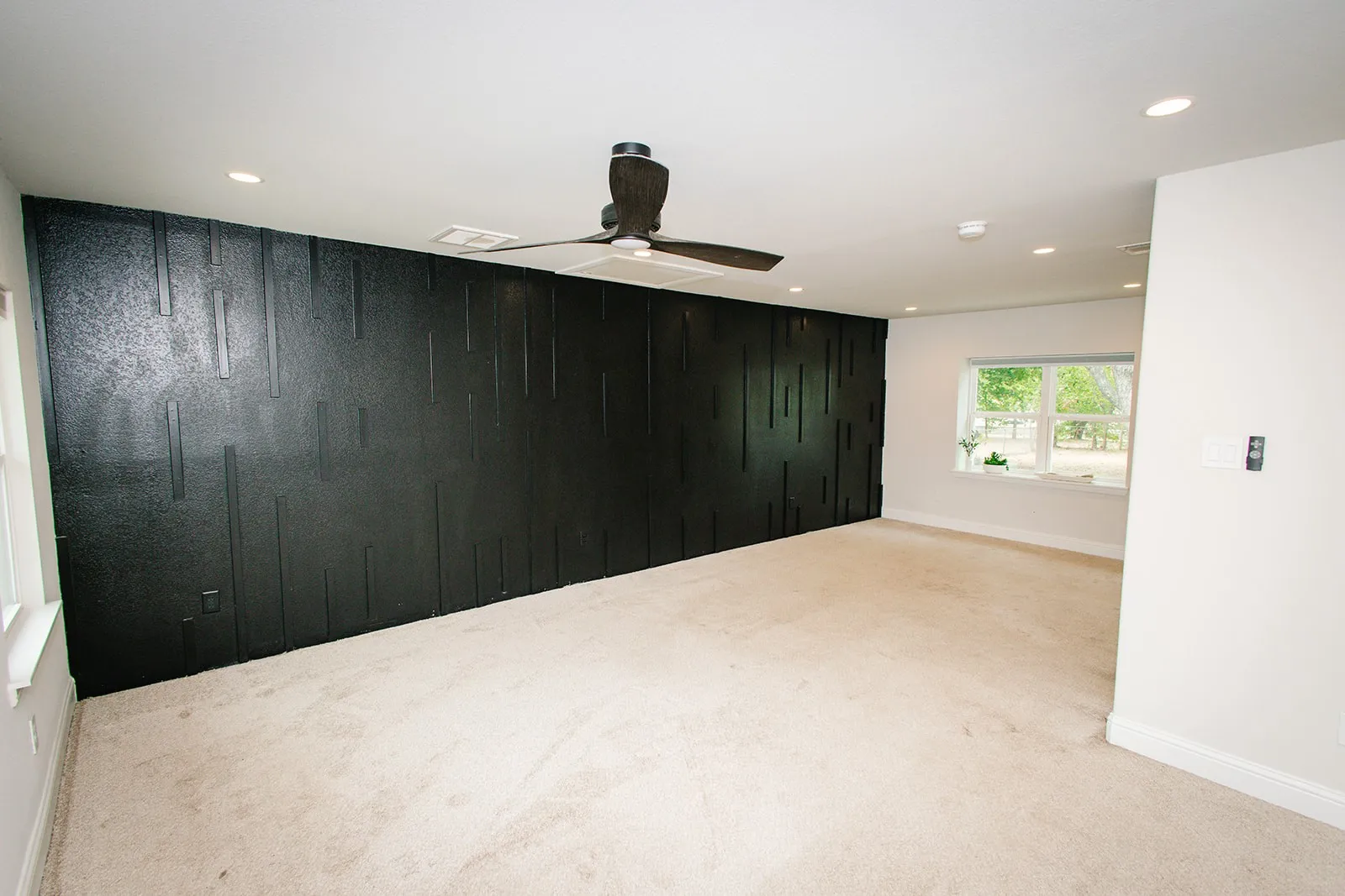 Master bedroom Textured accent wall, ceiling fan, recessed lighting, white trim, and multiple windows