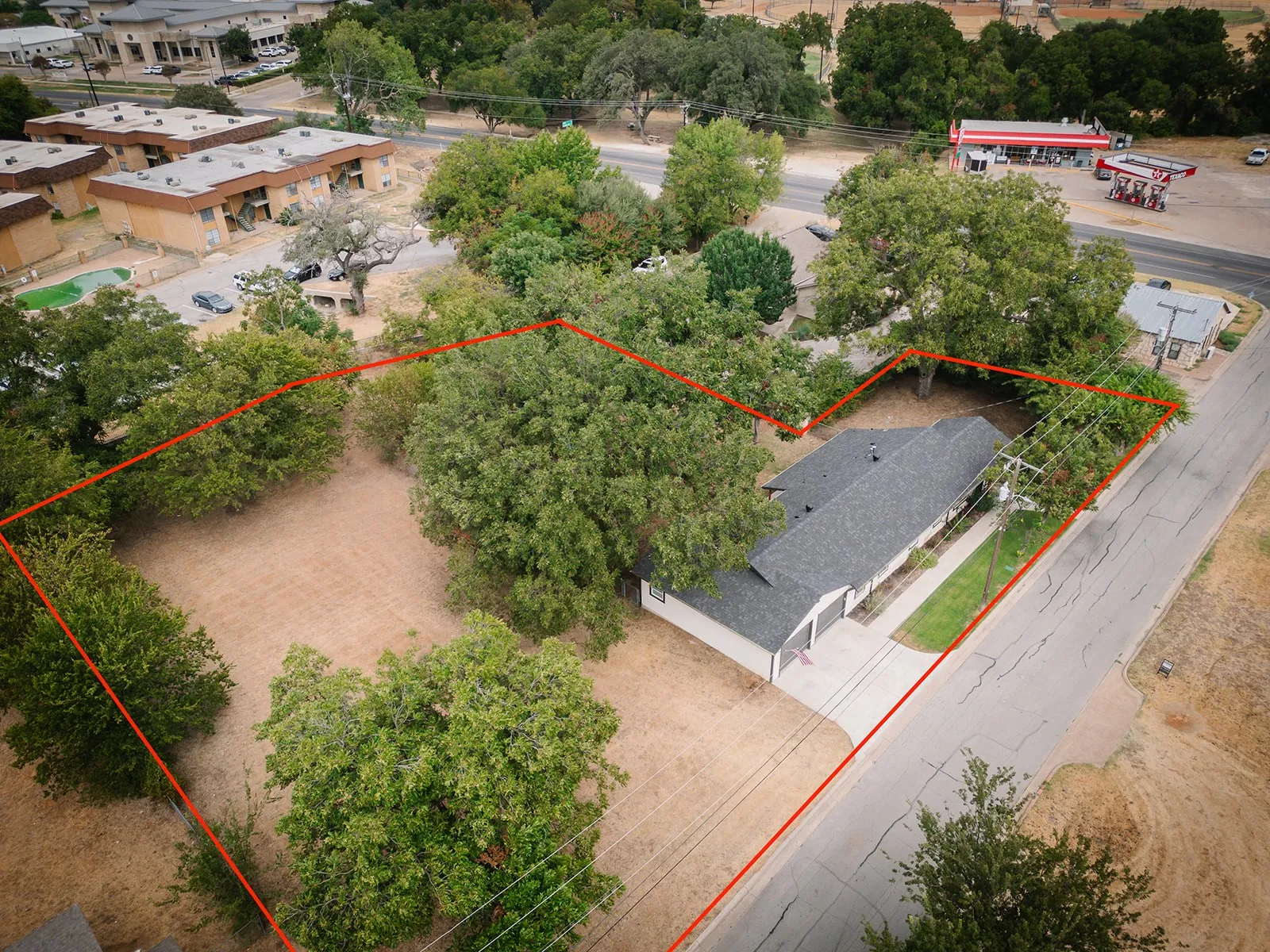 Single-story residence with an attached garage, paved driveway, and mature trees on the property