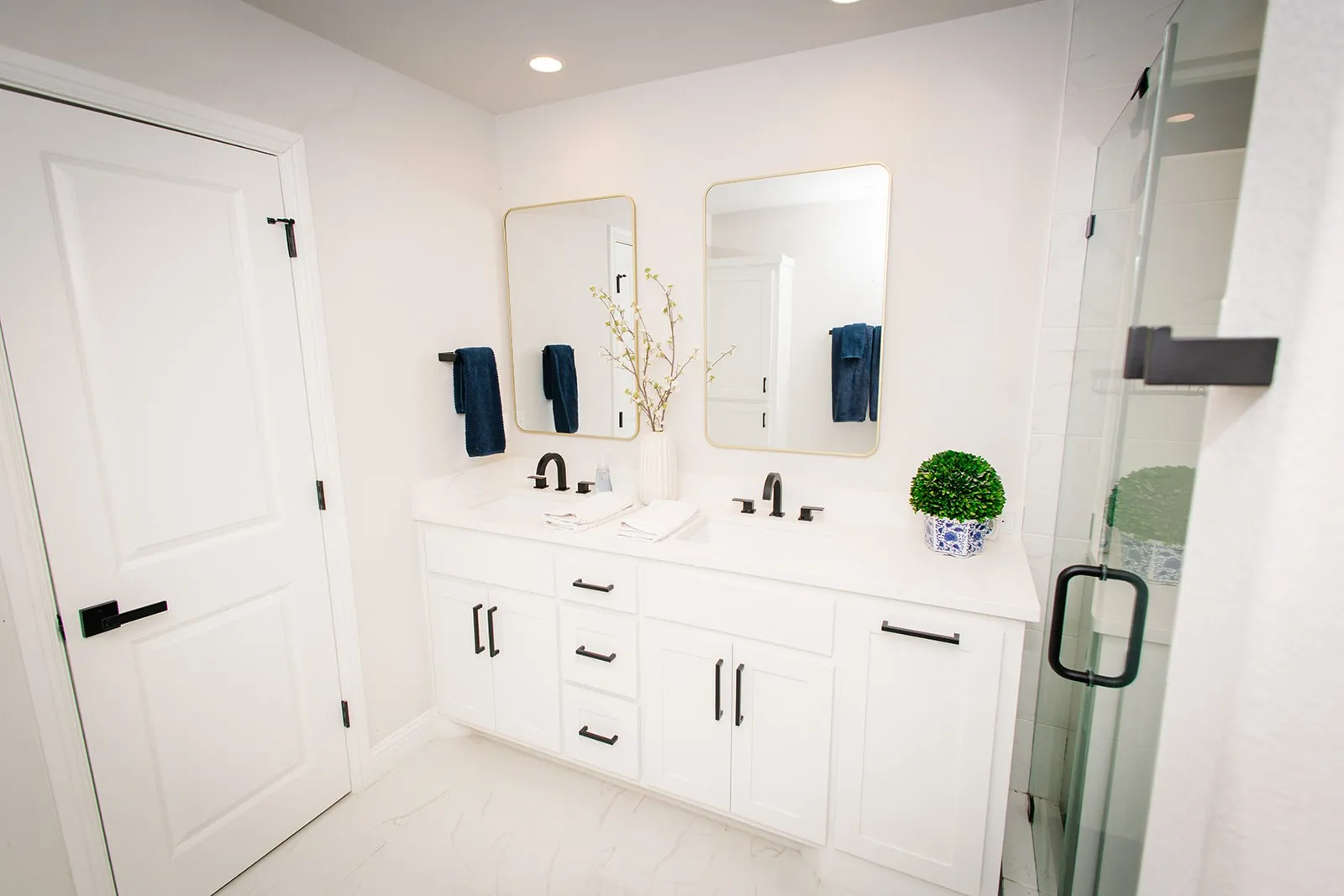 Master bath Dual vanity with integrated sinks, matte black fixtures, and gold-framed mirrors