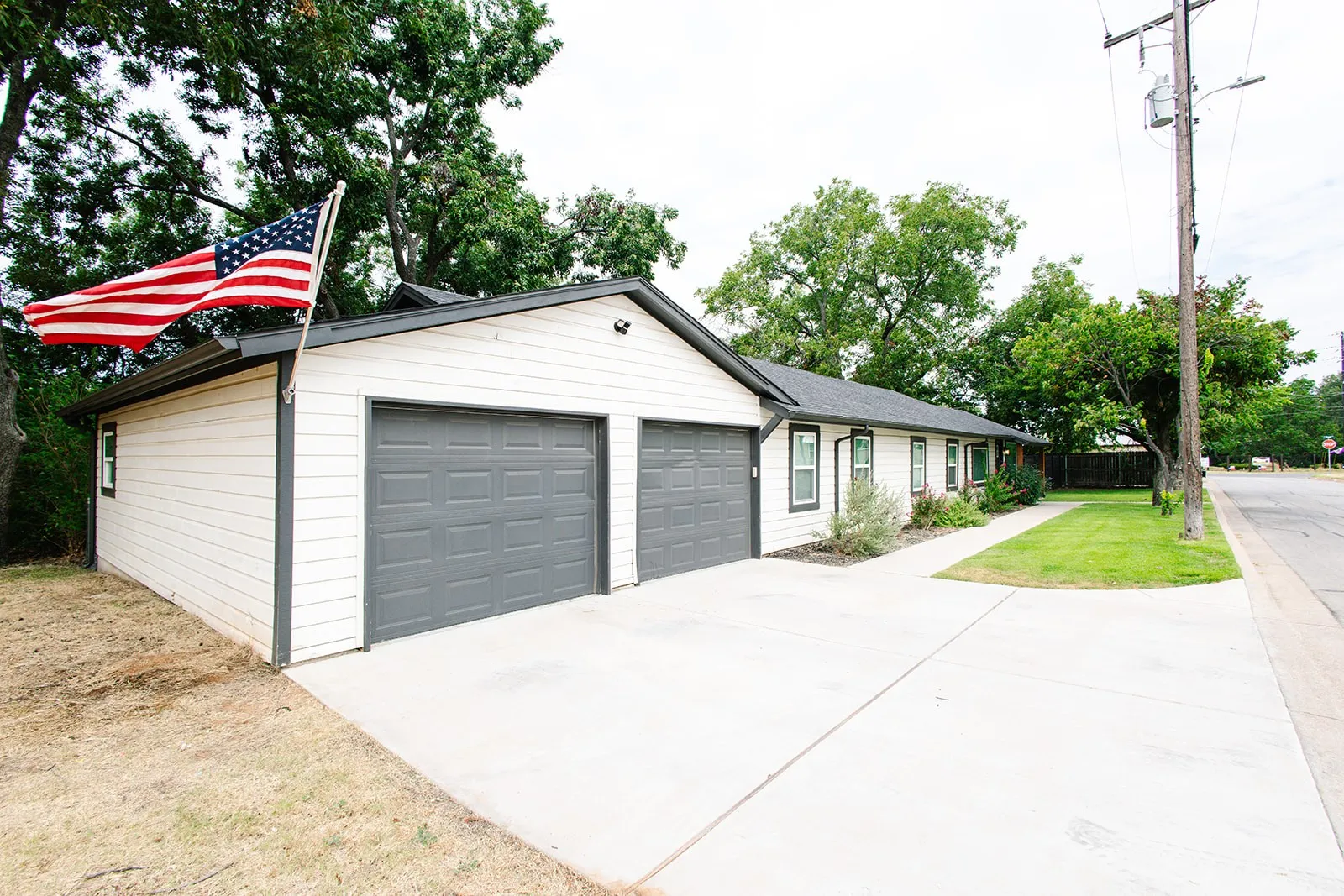 White horizontal siding with dark trim, two-car garage with panel doors, concrete driveway, and front walkway